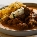 Kalbsrahmgulasch- Wiener Klassiker 2 Nahaufnahme vom cremigen Wiener Rahmgulasch mit goldbraunen Zwiebeln und heller Sauce